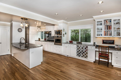 Inspiration for a mid-sized transitional galley medium tone wood floor eat-in kitchen remodel in Portland with an undermount sink, shaker cabinets, white cabinets, granite countertops, white backsplash, stone tile backsplash, stainless steel appliances and an island