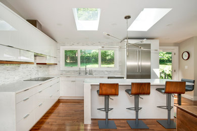 Inspiration for a contemporary medium tone wood floor and vaulted ceiling eat-in kitchen remodel in DC Metro with flat-panel cabinets, white cabinets, quartz countertops, white backsplash, stainless steel appliances, an island and white countertops