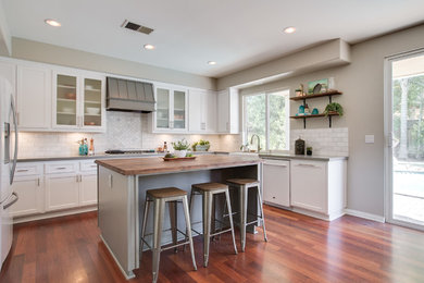 Eat-in kitchen - mid-sized contemporary u-shaped eat-in kitchen idea in Los Angeles with a farmhouse sink, recessed-panel cabinets, white cabinets, quartzite countertops, white backsplash, subway tile backsplash, white appliances and an island