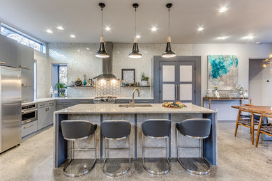 Large trendy l-shaped concrete floor open concept kitchen photo in Austin with a double-bowl sink, flat-panel cabinets, gray cabinets, quartz countertops, beige backsplash, mosaic tile backsplash, stainless steel appliances and an island