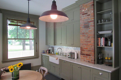 Kitchen - mid-sized traditional medium tone wood floor kitchen idea in New York with a farmhouse sink, flat-panel cabinets, green cabinets, marble countertops, subway tile backsplash and stainless steel appliances