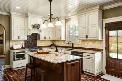 Inspiration for a large timeless l-shaped brick floor and red floor eat-in kitchen remodel in New Orleans with an undermount sink, raised-panel cabinets, beige cabinets, granite countertops, brown backsplash, travertine backsplash, stainless steel appliances and an island