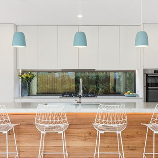 Large contemporary galley eat-in kitchen in Geelong with stainless steel appliances, medium hardwood floors, with island, brown floor, white benchtop, an undermount sink, flat-panel cabinets, white cabinets and window splashback.