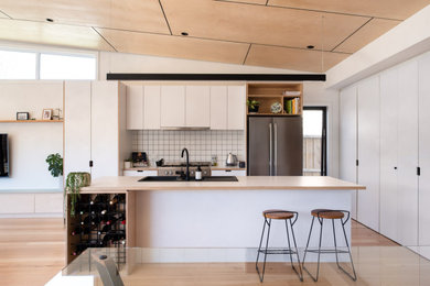 ジーロングにある高級な広いコンテンポラリースタイルのおしゃれなキッチン (白いキャビネット、白いキッチンパネル、セラミックタイルのキッチンパネル、シルバーの調理設備、ベージュのキッチンカウンター) の写真