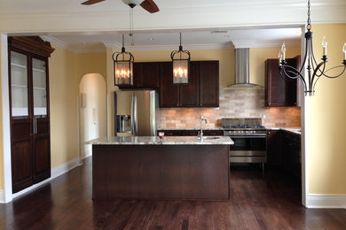 Eat-in kitchen - large transitional l-shaped medium tone wood floor eat-in kitchen idea in New Orleans with a double-bowl sink, shaker cabinets, granite countertops, multicolored backsplash, stone tile backsplash, stainless steel appliances, an island and medium tone wood cabinets
