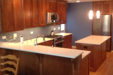 シカゴにある高級な中くらいなコンテンポラリースタイルのおしゃれなキッチン (アンダーカウンターシンク、落し込みパネル扉のキャビネット、中間色木目調キャビネット、珪岩カウンター、青いキッチンパネル、ガラスタイルのキッチンパネル、シルバーの調理設備、淡色無垢フローリング) の写真