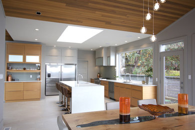 Eat-in kitchen - large modern galley porcelain tile and white floor eat-in kitchen idea in Vancouver with an undermount sink, flat-panel cabinets, light wood cabinets, quartz countertops, stainless steel appliances, an island and white countertops