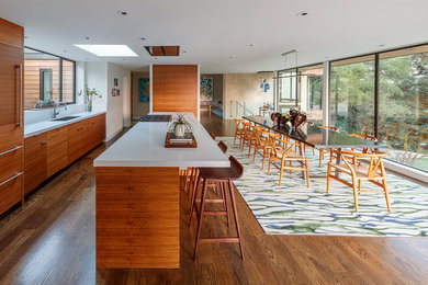 Inspiration for a huge mid-century modern single-wall medium tone wood floor and turquoise floor eat-in kitchen remodel in San Francisco with a drop-in sink, flat-panel cabinets, medium tone wood cabinets, quartz countertops, white backsplash, stone slab backsplash, paneled appliances and an island