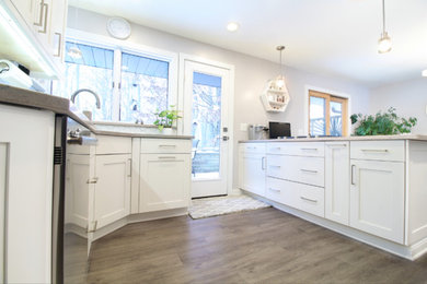 Large trendy u-shaped vinyl floor and gray floor eat-in kitchen photo in Other with an undermount sink, flat-panel cabinets, white cabinets, quartz countertops, white backsplash, ceramic backsplash, stainless steel appliances and a peninsula