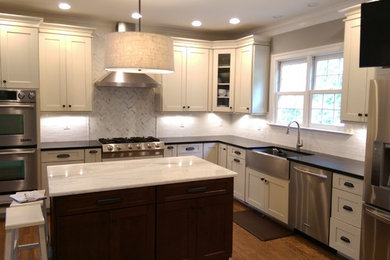 Example of a classic medium tone wood floor kitchen design in DC Metro with a farmhouse sink, shaker cabinets, white cabinets, granite countertops, white backsplash, subway tile backsplash, stainless steel appliances and two islands
