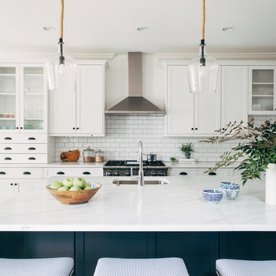 Galley kitchen photo in DC Metro with an undermount sink, shaker cabinets, white cabinets, white backsplash, subway tile backsplash, stainless steel appliances, an island and white countertops