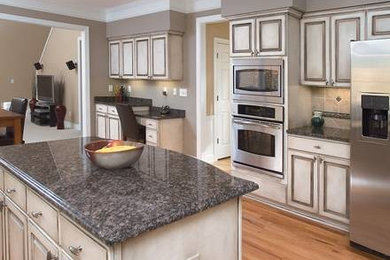 Eat-in kitchen - mid-sized traditional single-wall porcelain tile and beige floor eat-in kitchen idea in Atlanta with white cabinets, granite countertops, beige backsplash, stainless steel appliances, an island, raised-panel cabinets and porcelain backsplash