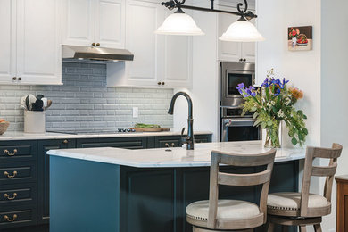 ポートランドにある高級な中くらいなトランジショナルスタイルのおしゃれなキッチン (エプロンフロントシンク、レイズドパネル扉のキャビネット、青いキャビネット、クオーツストーンカウンター、青いキッチンパネル、磁器タイルのキッチンパネル、シルバーの調理設備、淡色無垢フローリング、茶色い床、白いキッチンカウンター) の写真