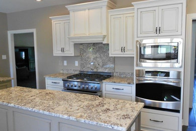 Inspiration for a timeless galley eat-in kitchen remodel in Louisville with an undermount sink, recessed-panel cabinets, white cabinets, granite countertops, stone slab backsplash and stainless steel appliances