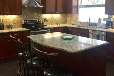 Ejemplo de cocina comedor de tamaño medio con salpicadero multicolor, electrodomésticos de acero inoxidable, una isla y suelo marrón