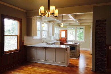 Inspiration for a mid-sized craftsman u-shaped light wood floor eat-in kitchen remodel in Sacramento with a farmhouse sink, raised-panel cabinets, white cabinets, granite countertops, white backsplash, subway tile backsplash, stainless steel appliances and an island