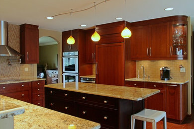 Example of a mid-sized trendy u-shaped medium tone wood floor and brown floor enclosed kitchen design in Other with shaker cabinets, dark wood cabinets, granite countertops, beige backsplash, mosaic tile backsplash, stainless steel appliances and an island