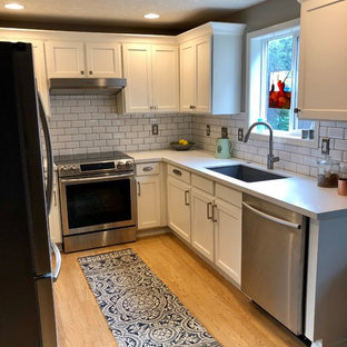 Immagine di una piccola cucina ad U chic chiusa con lavello sottopiano, ante con riquadro incassato, ante bianche, top in quarzo composito, paraspruzzi con piastrelle diamantate, elettrodomestici in acciaio inossidabile, parquet chiaro, nessuna isola, pavimento giallo e top bianco