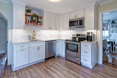 Example of a small country l-shaped medium tone wood floor and brown floor enclosed kitchen design in Portland with an undermount sink, shaker cabinets, yellow cabinets, quartz countertops, white backsplash, stone tile backsplash, no island and white countertops