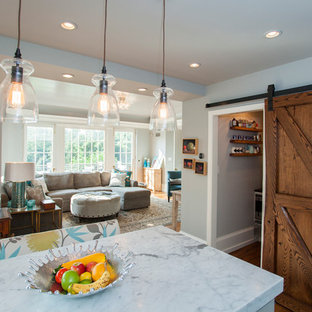 Example of a mid-sized cottage l-shaped medium tone wood floor eat-in kitchen design in Philadelphia with a farmhouse sink, shaker cabinets, white cabinets, marble countertops, white backsplash, subway tile backsplash, stainless steel appliances and an island