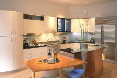 This is an example of a large contemporary l-shaped open plan kitchen in Edinburgh with an integrated sink, flat-panel cabinets, white cabinets, granite worktops, glass sheet splashback, stainless steel appliances, medium hardwood flooring and an island.