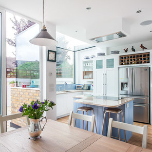 Ispirazione per una cucina abitabile country con ante in stile shaker, ante bianche, paraspruzzi blu, pavimento in legno massello medio, isola e elettrodomestici in acciaio inossidabile