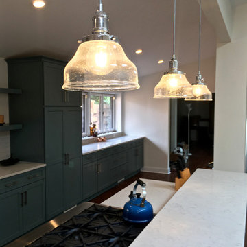 Glass-globed pendants above the island to define the kitchen in an open manner.