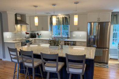 Example of a large classic l-shaped medium tone wood floor and beige floor open concept kitchen design in Boston with a double-bowl sink, shaker cabinets, white cabinets, quartz countertops, blue backsplash, glass tile backsplash, stainless steel appliances, an island and gray countertops