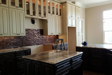 Bild på ett avskilt, mellanstort funkis u-kök, med luckor med upphöjd panel, brunt stänkskydd, vita skåp, stänkskydd i stickkakel, rostfria vitvaror och en köksö