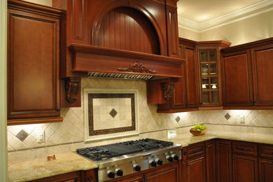 Inredning av ett klassiskt stort kök, med luckor med upphöjd panel, granitbänkskiva, beige stänkskydd, rostfria vitvaror, skåp i mörkt trä, stänkskydd i stenkakel och en köksö