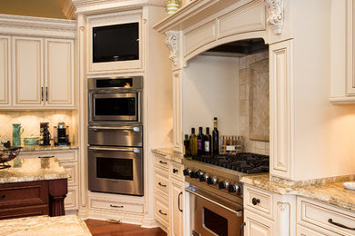 ニューヨークにある高級な中くらいなトラディショナルスタイルのおしゃれなキッチン (レイズドパネル扉のキャビネット、白いキャビネット、御影石カウンター、ベージュキッチンパネル、石タイルのキッチンパネル、シルバーの調理設備、無垢フローリング) の写真