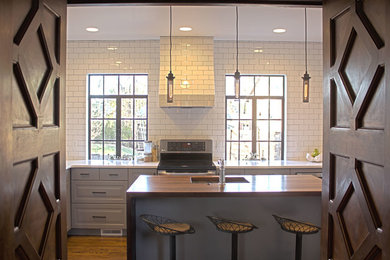 Idéer för eklektiska kök, med en enkel diskho, luckor med upphöjd panel, grå skåp, bänkskiva i kvarts, vitt stänkskydd, stänkskydd i tunnelbanekakel, rostfria vitvaror, mellanmörkt trägolv och en köksö