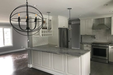 Inspiration for a mid-sized modern l-shaped porcelain tile and gray floor eat-in kitchen remodel in New York with a farmhouse sink, shaker cabinets, white cabinets, granite countertops, white backsplash, glass tile backsplash, stainless steel appliances and a peninsula