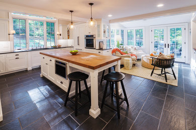 Inspiration for a timeless u-shaped eat-in kitchen remodel in Philadelphia with a double-bowl sink, white cabinets, subway tile backsplash, stainless steel appliances and an island