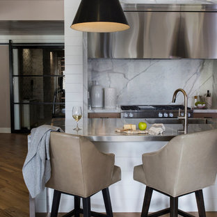 Photo of a mid-sized transitional kitchen in Other with stainless steel benchtops, white splashback, stone slab splashback, stainless steel appliances, with island, an integrated sink and dark hardwood floors.