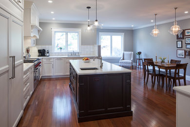 Example of a large trendy medium tone wood floor kitchen design in San Francisco with an integrated sink, recessed-panel cabinets, white backsplash, ceramic backsplash, stainless steel appliances and an island
