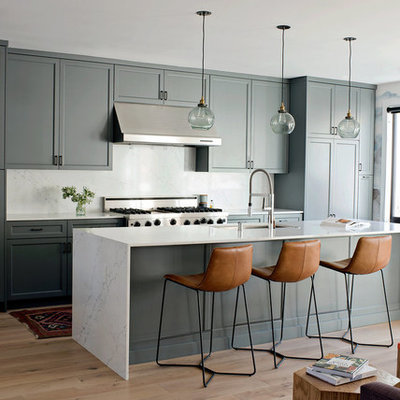 Transitional galley light wood floor open concept kitchen photo in San Francisco with an undermount sink, shaker cabinets, green cabinets, stainless steel appliances, an island and white countertops