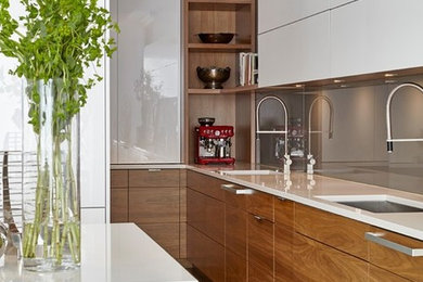 Example of a trendy kitchen design in Toronto with an undermount sink, flat-panel cabinets, medium tone wood cabinets, quartzite countertops, gray backsplash, glass sheet backsplash, paneled appliances and two islands