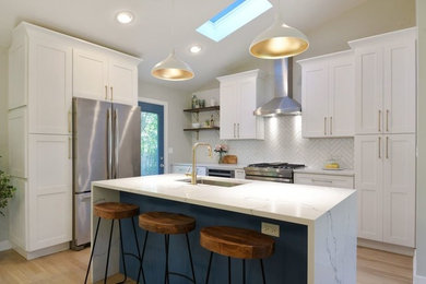 Inspiration for a transitional light wood floor and beige floor kitchen remodel in Chicago with an undermount sink, shaker cabinets, white cabinets, white backsplash, stainless steel appliances, an island and white countertops