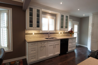 Eat-in kitchen - mid-sized transitional u-shaped dark wood floor eat-in kitchen idea in Toronto with a double-bowl sink, shaker cabinets, white cabinets, granite countertops, beige backsplash, stone tile backsplash, black appliances and no island