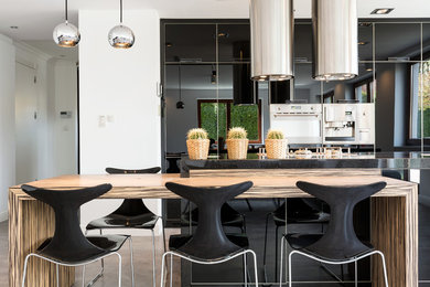 Imagen de cocina comedor moderna con puertas de armario negras, suelo de baldosas de cerámica, una isla y suelo beige