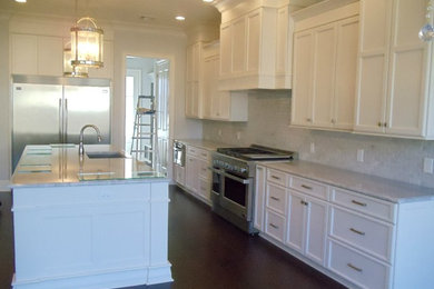 Example of a large transitional single-wall dark wood floor open concept kitchen design in New Orleans with an undermount sink, recessed-panel cabinets, white cabinets, stainless steel appliances and an island