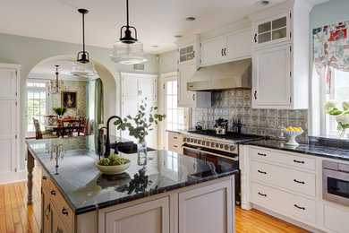 Example of a large farmhouse l-shaped medium tone wood floor and orange floor kitchen design in Philadelphia with a farmhouse sink, white cabinets, quartzite countertops, metallic backsplash, metal backsplash, stainless steel appliances, an island and shaker cabinets