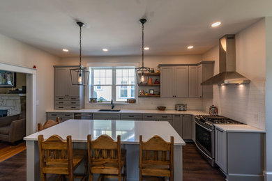 Mid-sized transitional l-shaped laminate floor and brown floor eat-in kitchen photo in Philadelphia with an undermount sink, shaker cabinets, gray cabinets, quartz countertops, white backsplash, ceramic backsplash, stainless steel appliances, an island and white countertops