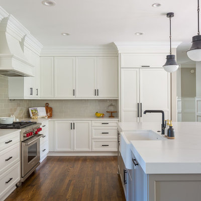 Inspiration for a transitional l-shaped medium tone wood floor and brown floor eat-in kitchen remodel in Raleigh with quartz countertops, an island, white countertops, a farmhouse sink, recessed-panel cabinets, white cabinets, beige backsplash, subway tile backsplash and paneled appliances