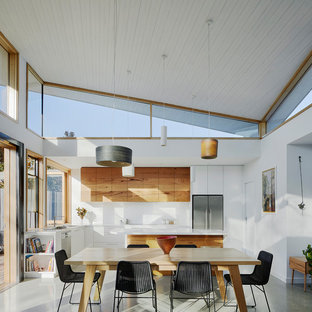 This is an example of a mid-sized contemporary l-shaped eat-in kitchen in Melbourne with white splashback, multiple islands, grey floor, a drop-in sink, flat-panel cabinets, medium wood cabinets and stainless steel appliances.