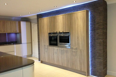 This is an example of a medium sized contemporary u-shaped kitchen/diner in Other with a submerged sink, flat-panel cabinets, white cabinets, granite worktops, glass sheet splashback, integrated appliances, ceramic flooring and no island.
