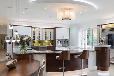 This is an example of a large contemporary u-shaped open plan kitchen in Other with a built-in sink, flat-panel cabinets, medium wood cabinets, engineered stone countertops, green splashback, glass sheet splashback, integrated appliances, an island, white worktops and beige floors.