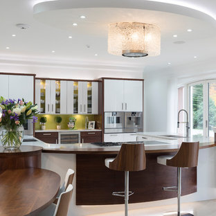 This is an example of a large contemporary u-shaped open plan kitchen in Other with a built-in sink, flat-panel cabinets, medium wood cabinets, engineered stone countertops, green splashback, glass sheet splashback, integrated appliances, an island, white worktops and beige floors.