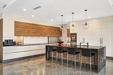 Exempel på ett stort modernt kök, med en undermonterad diskho, vita skåp, granitbänkskiva, grått stänkskydd, glaspanel som stänkskydd, svarta vitvaror, betonggolv och en köksö